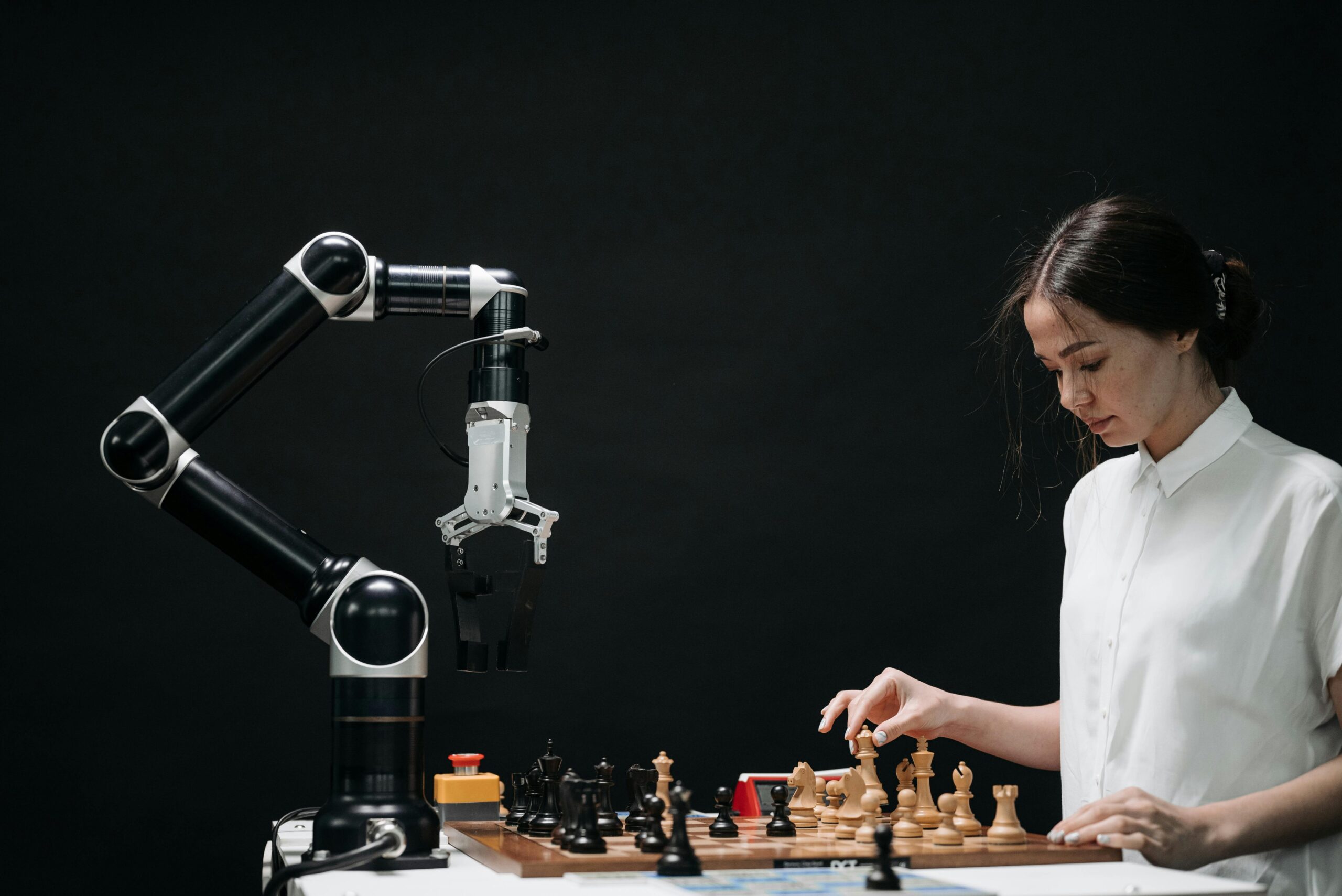 A woman plays chess against a robotic arm showcasing AI innovation in a modern setting